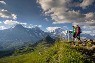Zwei Wanderer geniessen den Ausblick auf dem Männlichen auf Eiger, Mönch und Jungfrau.