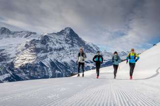 Zwei Läufer beim Winter Trail Running auf Grindelwald First, im Hintergrund der Eiger.