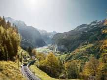 Die Wengernalpbahn unterwegs von Lauterbrunnen nach Wengen. Im Hintergrund das in Herbstfarben gehüllte Lauterbrunnental mit dem Staubbachfall.
