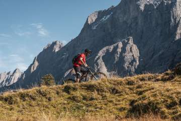 Ein Mann auf einem Mountainbike fährt ein Biketrail hinauf.