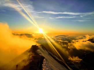 Die untergehende Sonne ermöglich wunderschöne Aufnahmen vom Schilthorn. Die umliegende Bergwelt versinkt in den golden gefärbten Wolken.