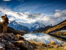 Eine Person steht im Herbst vor dem Bachalpsee, mit den umliegenden Bergen im Hintergrund.